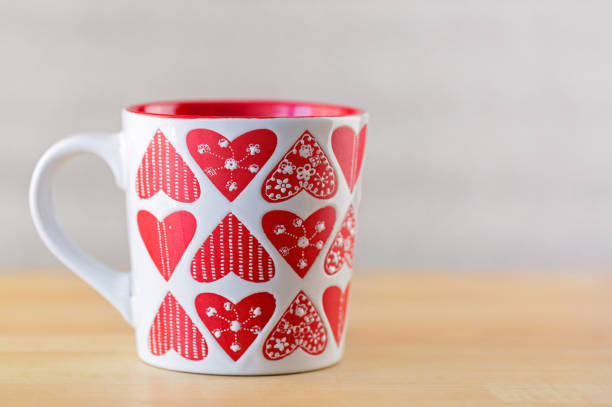 istock White cup on wooden background. Mug with heart shape patterns 918437404