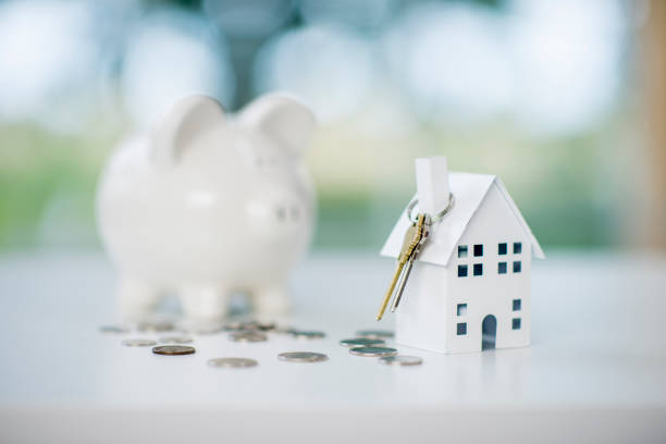 Saving For A House A miniature house model is sitting on a desk. A piggy bank and coins are besides the house. The scene symbolizes saving up for a new house. money house stock pictures, royalty-free photos & images