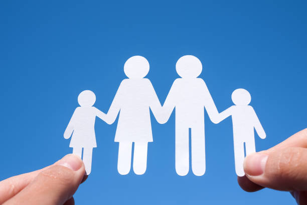 istock Paper family in two hands against a blue sky background 918443542