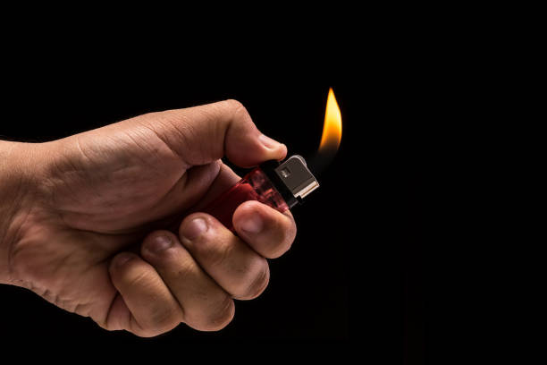 istock Hand holding burning gas lighter. Studio shot isolated on black background 918450374