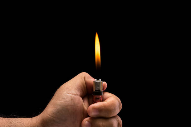 istock Hand holding burning gas lighter. Studio shot isolated on black background 918450400