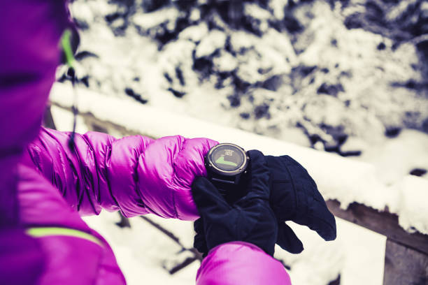 alpinista de mulher olhando esportes relógio no inverno bosques e montanhas - gps watch - fotografias e filmes do acervo