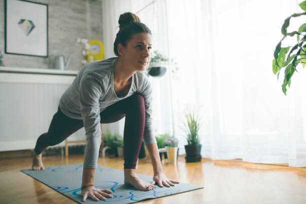 Yoga At Home Young woman practicing iyengar yoga at home in her living room. exercise routine stock pictures, royalty-free photos & images