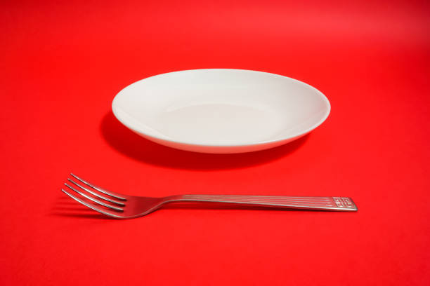 istock a white dish and a folk and a knife. restaurant image. red background. 918458736
