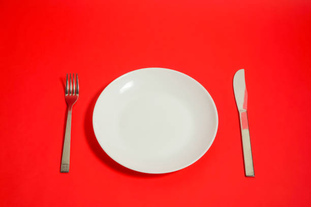istock a white dish and a folk and a knife. restaurant image. red background. 918458762