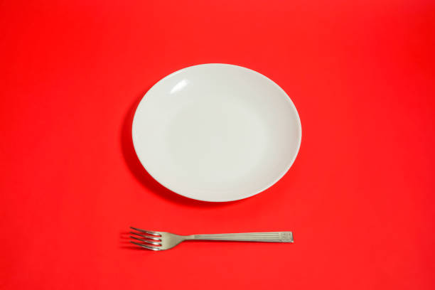 istock a white dish and a folk and a knife. restaurant image. red background. 918458766