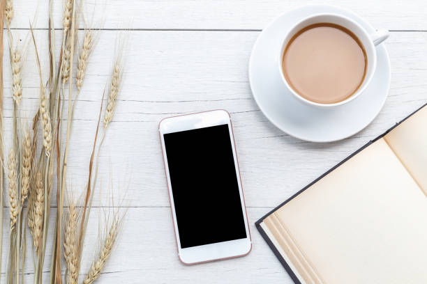 istock Top view coffee, smartphone and empty book on white wooden table 918459136