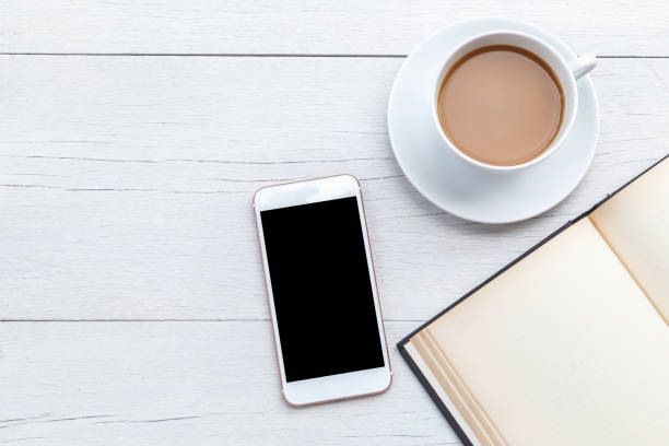 istock Top view coffee, smartphone and empty book on white wooden table 918459166