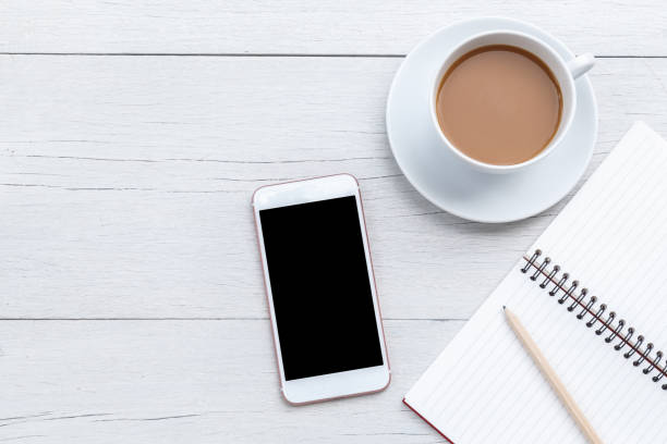 istock Top view coffee, smartphone and empty book on white wooden table 918459190