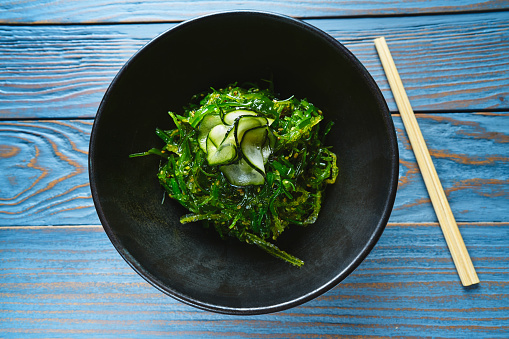 Algae salad with cucumber sesame and soya in black bowl