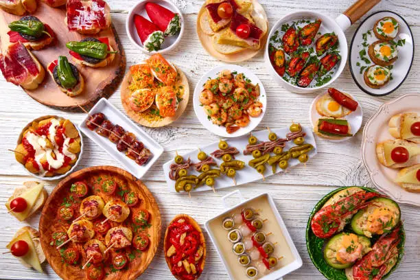 Tapas mix and pinchos food from Spain recipes also pintxos on a white wood board