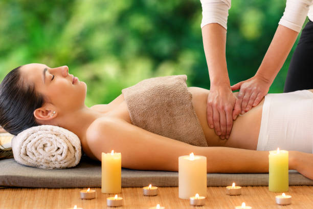 frau mit aromaöl-massage - abdomen women massaging human hand stock-fotos und bilder