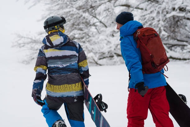 istock Two happy snowboarders is walking, talking and laughing 918480648