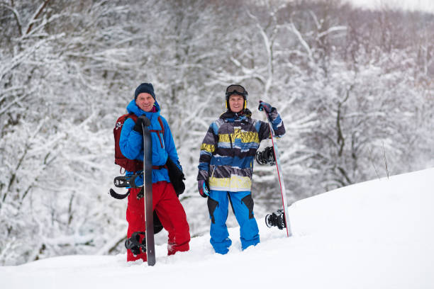 istock Two joyful snowboarders rest among snow covered trees 918480660