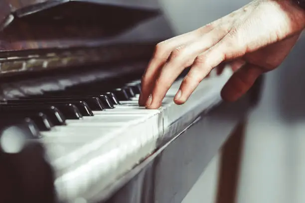 men's fingers on an old piano play