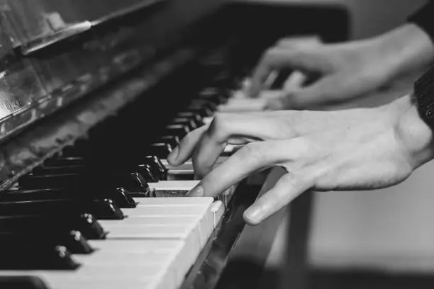 men's fingers on an old piano play