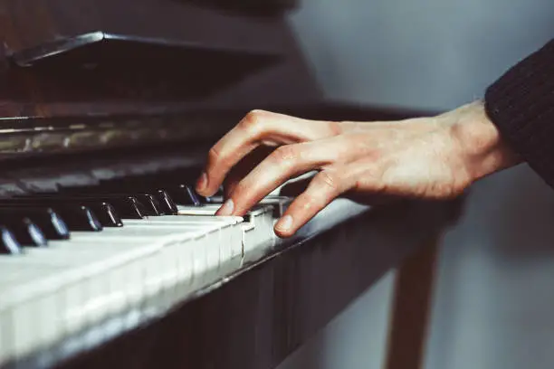 men's fingers on an old piano play