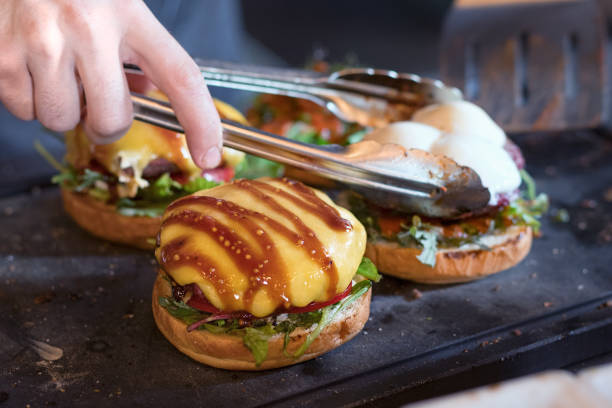 istock preparing burger adding the sauce on the cream cheese. Three burgers 918485432