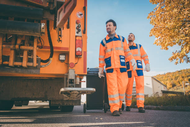 Two refuse collection workers loading garbage into waste truck stock photo