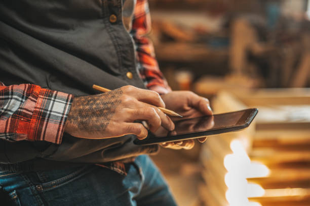 carpenter using tablet while working in his workshop pn furniture project - carpenters pencil imagens e fotografias de stock