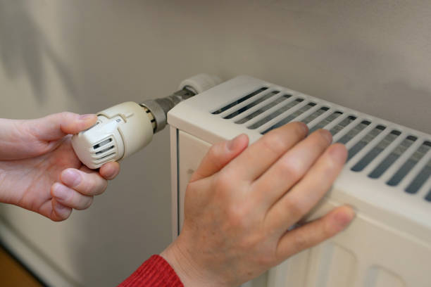istock Woman Adjusting Thermostat On Radiator 918492742