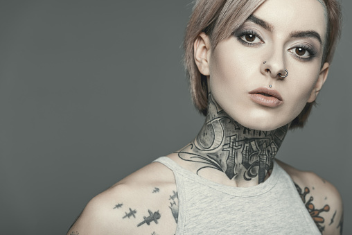 attractive tattooed girl, isolated on grey