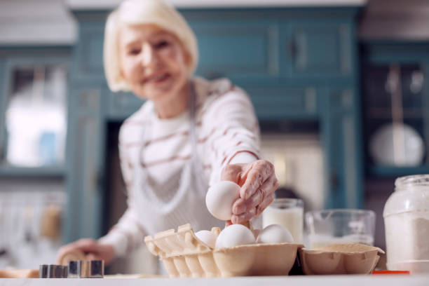 istock Elderly woman taking egg from carton for dough-making 918494528
