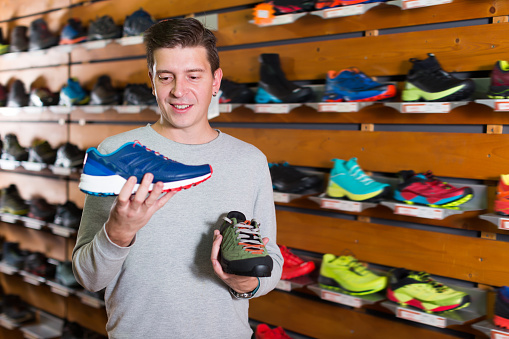 Cheerful man chooses shoes in a sports shop