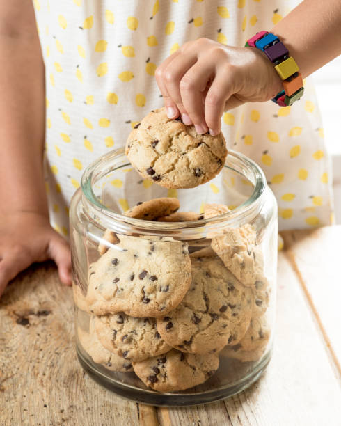 istock Child taking chocolate chip cookie from jar full of cookies 918497874