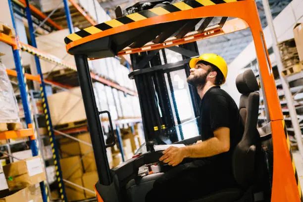 Photo of Warehouse worker doing logistics work with forklift loader