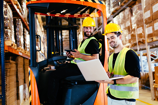 Warehouse workers working together with forklift loader trasnporter