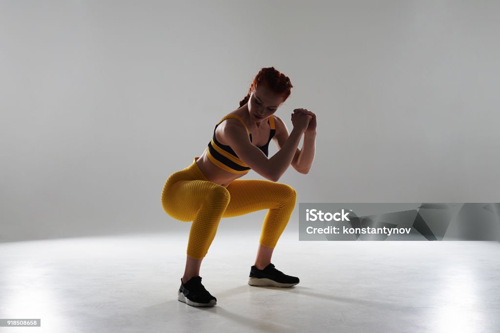 woman in sportswear doing squats woman in sportswear doing squats in studio Squatting Position Stock Photo