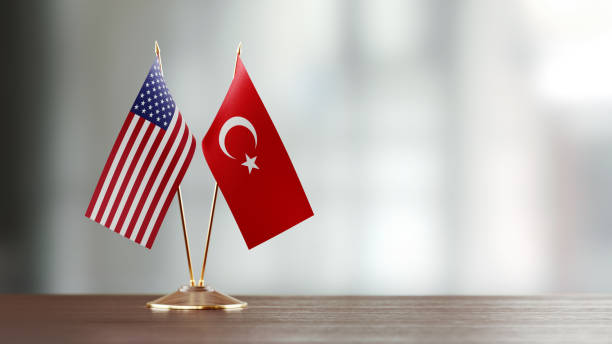 American And Turkish Flag Pair On A Desk Over Defocused Background