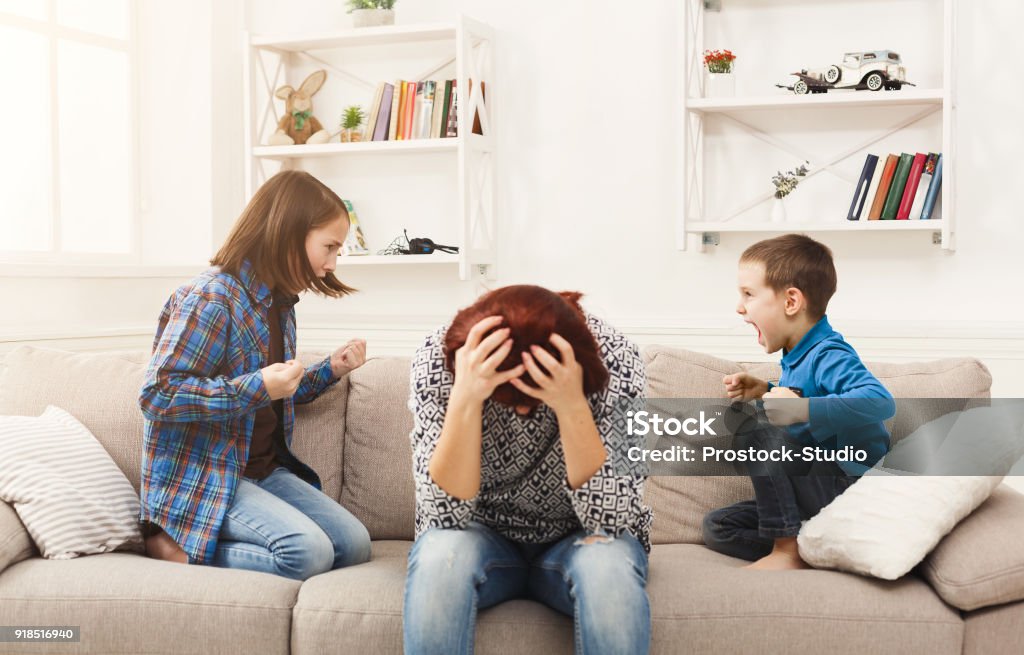 Kids having quarrel over tired mother Kids having quarrel over tired mother. Mom is depressed by screaming of children. Problems of motherhood, copy space Child Stock Photo