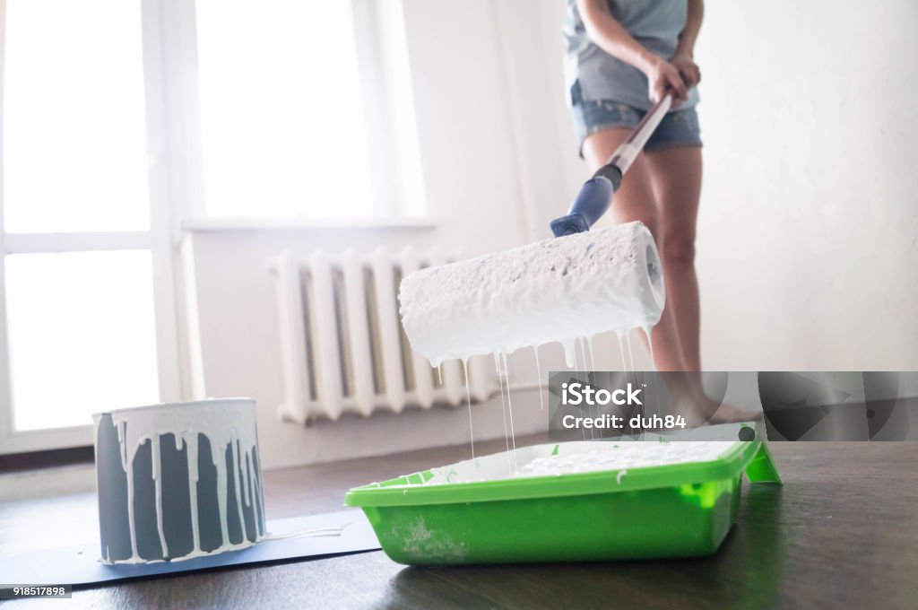 close-up roller with inlays and drops of white paint close-up roller with inlays and drops of white paint in the hands of a girl Painting - Activity Stock Photo