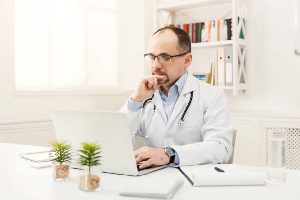 istock Serious doctor in glasses sitting at the desktop 918518524