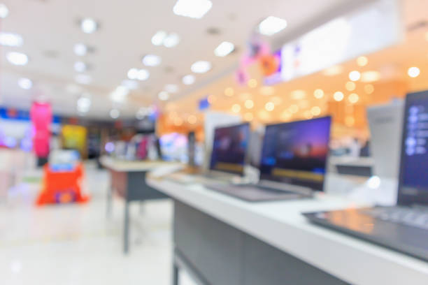 portátil ordenador sobre mesa en tienda de electrónica en centro comercial resumen blur defocused fondo - tienda de electrónica fotografías e imágenes de stock