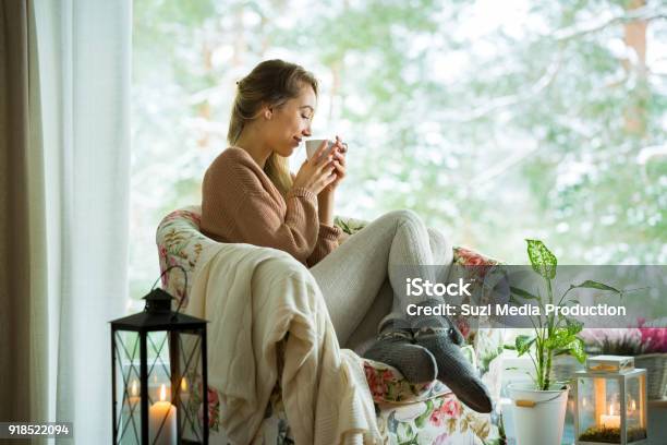 Young Woman By The Window With Cup Of Hot Coffee Stock Photo - Download Image Now - Winter, Tea - Hot Drink, Domestic Life