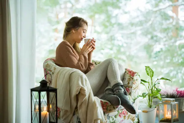 Photo of Young woman by the window with cup of hot coffee