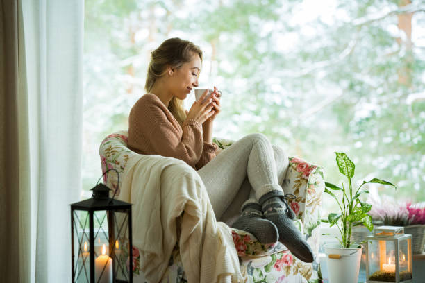 jovem mulher pela janela com uma xícara de café quente - window home interior women people - fotografias e filmes do acervo