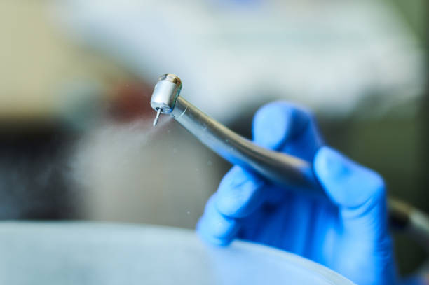 istock Dentist's hands with blue gloves working with dental drill in dental office. 918522410