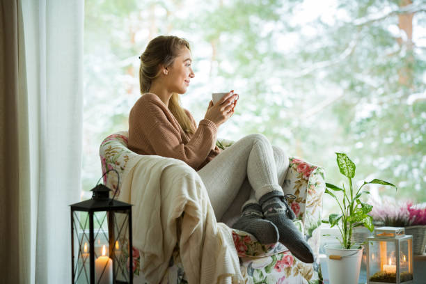 ホット コーヒーのカップを持つウィンドウごとに若い女性 - christmas textile blanket decoration ストックフォトと画像