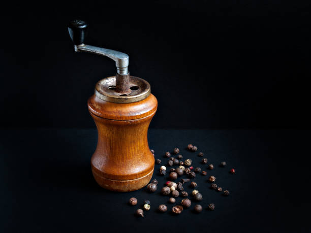 Old wooden pepper mill on a black background