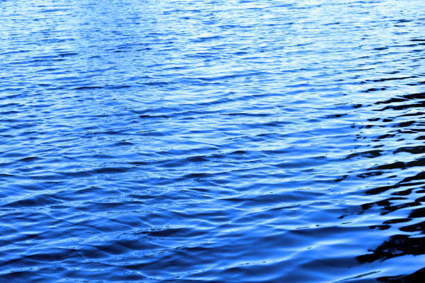 istock Vivid blue water with sun reflections background texture 918525578