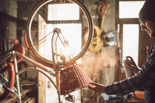 Young man painting bike basket in the garage