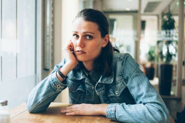 istock Pensive young woman sitting in cafe alone 918529672