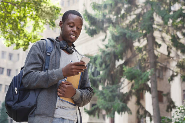Happy african-american student texting in university campus