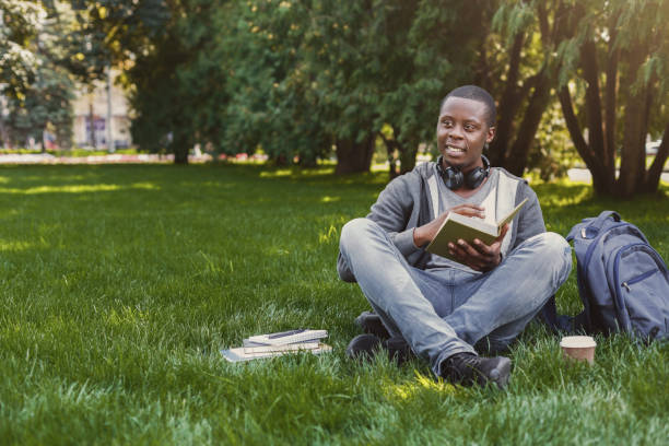istock African-american student reading book in campus on grass 918536676