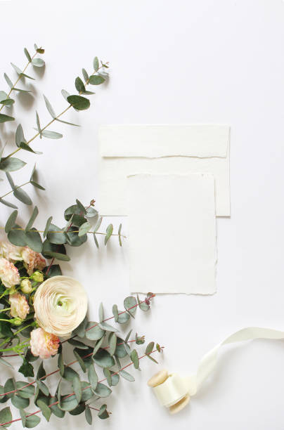 istock Feminine wedding, birthday desktop mock-ups. Blank craft paper greeting card, envelope. Eucalyptus branches, pink roses and Persian buttercup flowers. White table background. Flat lay, top view 918537254