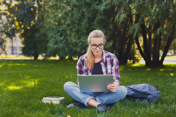 istock Happy young woman using laptop in park 918537392